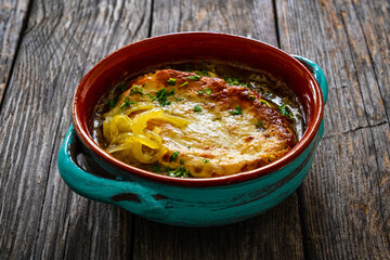 Onion soup with roasted bread with cheese on wooden table
