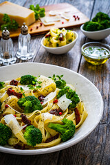 Pasta with broccoli, parmesan and sun dried tomatoes on wooden table
