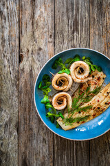 Marinated herring fillets with dill on wooden table
