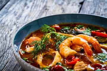 Seafood and fish soup on wooden table
