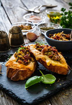 Tasty sandwiches - baked bread with cheese, olives, sun dried tomatoes and thyme on wooden table
