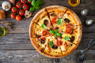 Circle pizza with boiled ham and  mushrooms on wooden table
