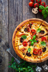 Circle pizza with boiled ham and  mushrooms on wooden table
