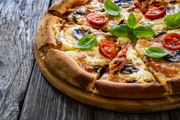 Circle pizza with boiled ham and  mushrooms on wooden table

