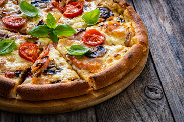 Circle pizza with boiled ham and  mushrooms on wooden table
