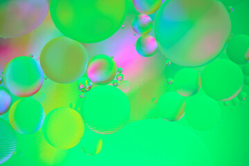 Multi colored abstract background with oil circles on water surface with a green background.