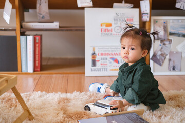 cute little baby girl sitting on the floor and playing toy in the living room alone at house. Kid Lifestyle concept.