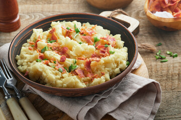Mashed potatoes. Bacon mashed potatoes with green onion, pepper and cheddar cheese in bowl on old wooden backgrounds. Delicious creamy mashed potatoes. Top view.