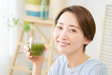家で青汁を飲む女性　カメラ目線
