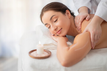 Obraz na płótnie Canvas Relaxed indian female enjoying shouders massage in modern spa