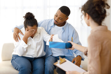 Black man comforting crying wife, couple attend family therapy