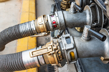 Devices attached to the mouths of a tanker truck to connect the discharge hoses, discharging normal diesel (diesel A) and subsidized diesel (diesel B or red) in the background.