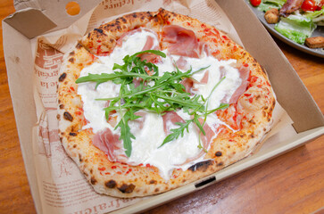 A baker making bread in the kitchenPizza with parma ham Italian style in a paper box