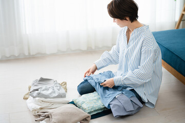 洗濯物を畳む若い女性　ライフスタイルイメージ © aijiro