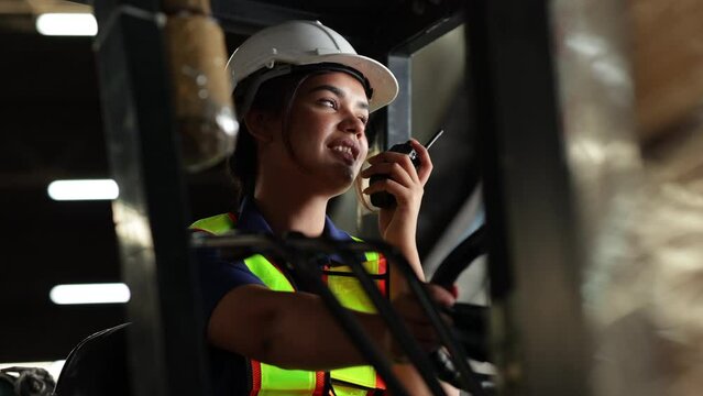 Indian woman driving a forklift and using a walkie-talkie. communication radio. Inventory and wholesale concept