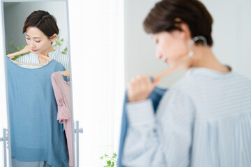 鏡の前で服選びをしている若い女性　ファッションイメージ