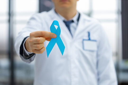 Doctor hand with blue prostate cancer awareness ribbon. Medicine oncology closeup sky symbol