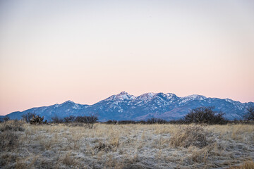Fototapeta premium Distant mountain range with hills covered in grass in the forground in Arizona.