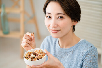ミックスナッツを食べる若い女性　飲食イメージ