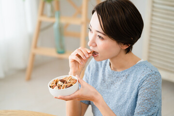 ミックスナッツを食べる若い女性　飲食イメージ
