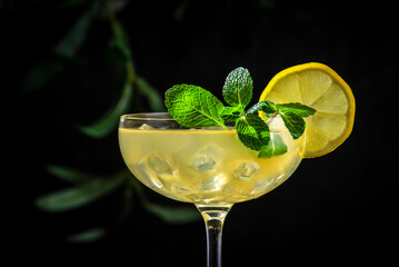 White lady alcoholic cocktail with dry gin, liquor, lemon juice and ice in wine glass. Black background, close-up