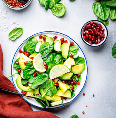 Fresh vegan salad with pineapple, spinach, avocado and pomegranate seeds, gray kitchen table, top view. Healthy eating, clean food, diet, weight loss concept