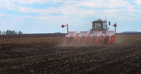 Fototapeta premium Seeding Machine Working in Field on the Farm. Agriculture. Tractor Seeder it Plants Seeds in the Ground. Tillage Equipment. 