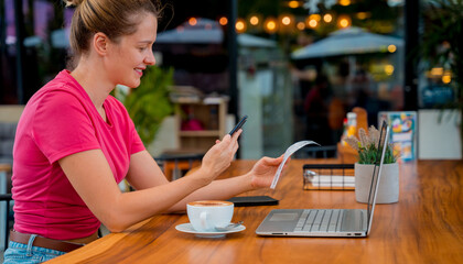 Woman using contactless payment by mobile phone with QR code at cafe