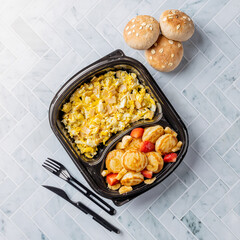 Healthy and delicious dish consisting of fluffy pancakes drizzled with honey and topped with fresh strawberries and bananas. Served with a side of bread for a perfect breakfast or brunch. Top View