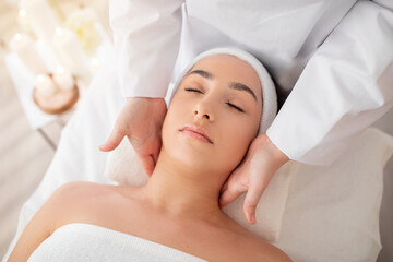 Fototapeta na wymiar Young indian female enjoying therapeutic neck massage in spa