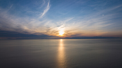 Sunset seascape. The red sun setting among the clouds. blue sky