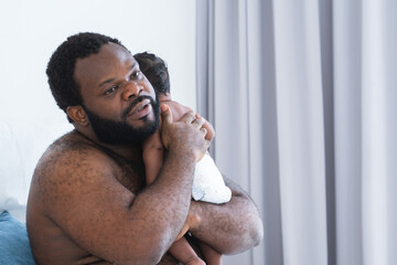 African middle aged bearded father is soothing newborn baby crying in his arms and shoulder in bedroom at home. Single dad hugging and try to pacify cute infant alone. Family bonding concept