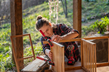 Young woman assembling wooden bamboo furniture for a terrace in a country house