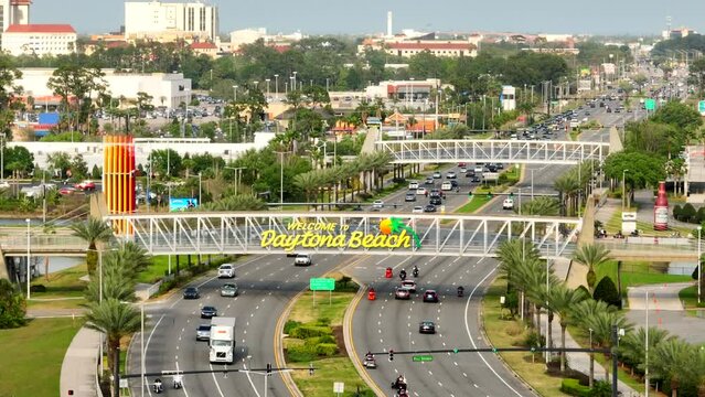 Welcome to Daytona Beach on a pedestrian overpass. 4k aerial drone video