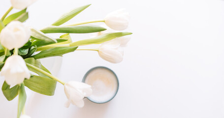 Fototapeta premium Bouquet of white tulips with cup of coffee on white background.