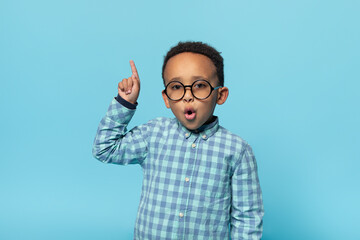 Great idea. Emotional black boy in eyeglasses pointing finger up and looking at camera, posing over...