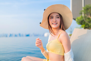 relax summer casual leisure asia woman female in swimwear chill on rattan pool bench lay down near swimming pool with infinity pool side on rooftop of building summer travel vacation sun bathing