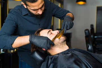 Young man at the barber shop shaving his beard