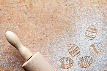 Easter eggs made of flour on chopping board with wooden rolling pin, easter baking background concept