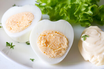 Hard boiled egg in shape of heart with mayonnaise and lettuce on plate