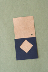 cardboard brown paper tag and square frame on rough green paper