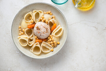 Plate of catalan escudella on a light-beige stone background, horizontal shot with copy space, above view