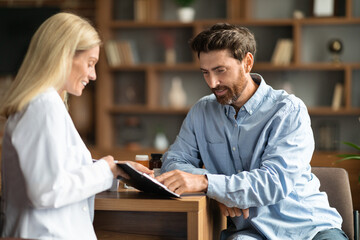 Male Patient Discussing Blood Test Results With Doctor During Checkup In Office