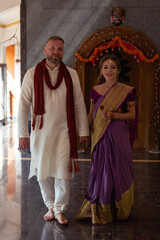 Obraz premium Wedding of a couple from Europe in India. A light skinned man in a traditional Indian men. white skin. Bride in beautiful sari with mehendi. Caucasian marriage. International couple.Lovely couple fit 