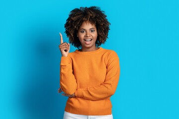 Inspired young black woman showing eureka gesture on blue
