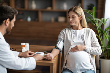 Gynecologist Doctor Wearing Uniform Measuring Blood Pressure For Pregnant Female Patient