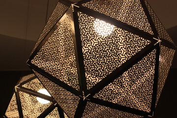 Modern cubic-shaped lamp ceiling burns brightly.  Large glass lamp in a metal frame and abstract rhythmic pattern