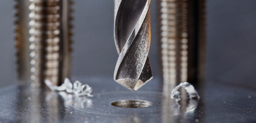 metal drill bit make holes in steel billet on industrial drilling machine. Metal work industry....