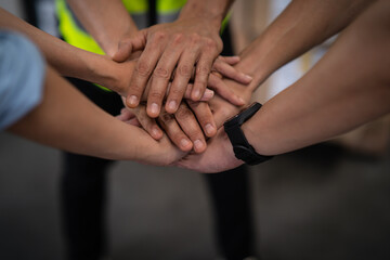 Close up view of warehouse workers putting their hands together. Stack of hands. Unity and teamwork.