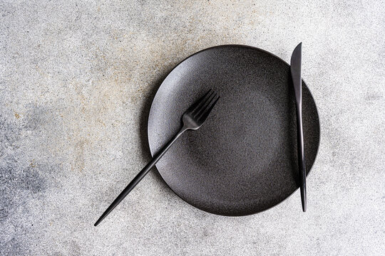 Minimalistic table on a concrete background with a plate a knife and a fork